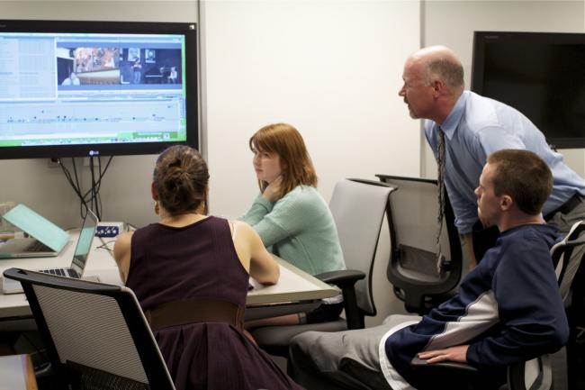 Students and professor editing a video together.